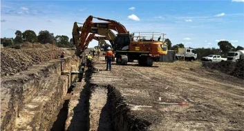 Excavator working alongside a pipeline trench